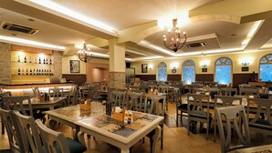 A restaurant with multiple tables and chairs, a bar area with bottles, and decorative lighting. - Cross Roads Inn (Bengaluru)