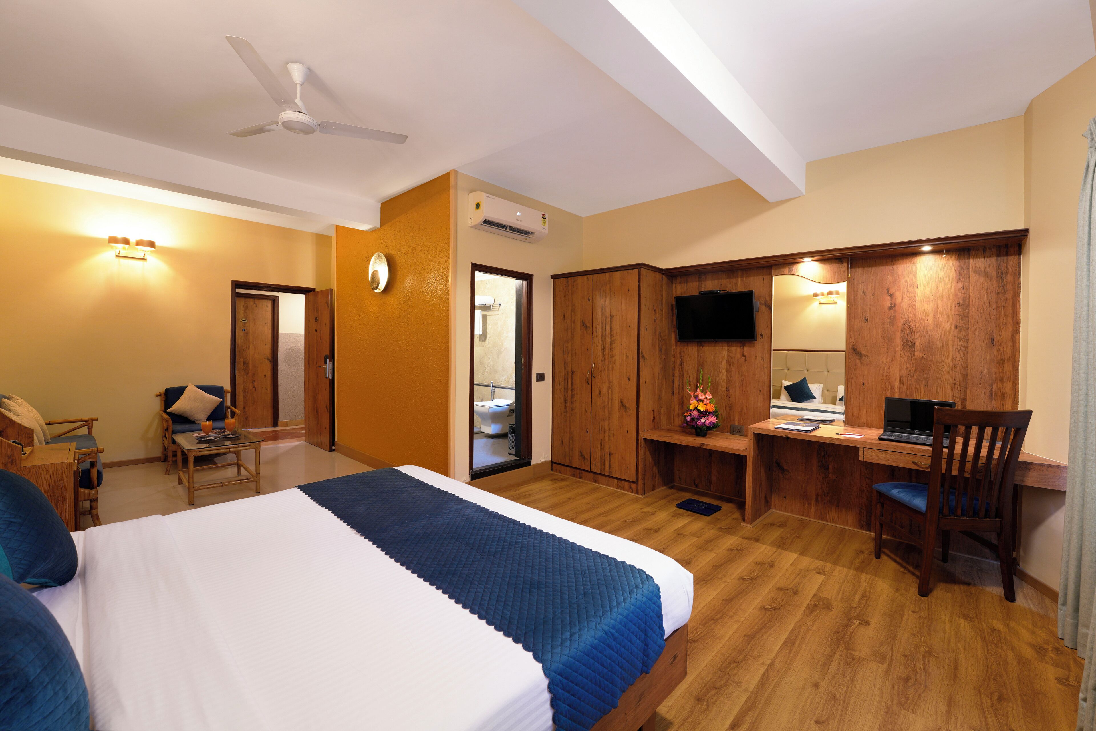 Hotelkamer met een bed, bureau, stoel, televisie en een badkamer zichtbaar door een open deur.