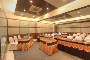 A conference room with multiple tables, white chairs, and brown tablecloths. - Hotel VT Paradise (Bengaluru)
