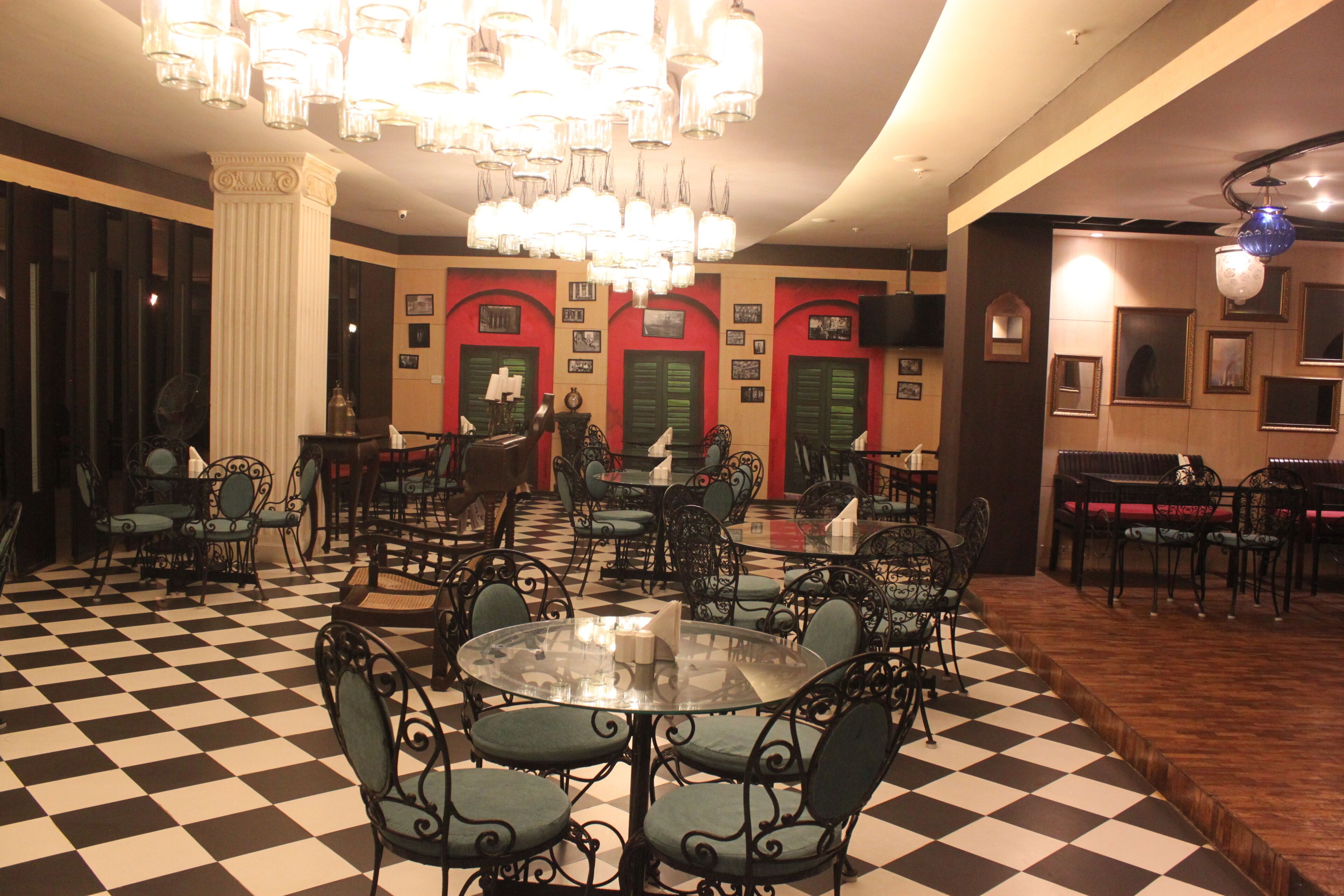 A hotel lobby with checkered flooring, multiple seating areas, and a chandelier.