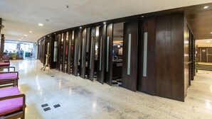 A hotel lobby with a curved wall, seating area with pink chairs, and a check-in counter. - The Lindsay (Kolkata)