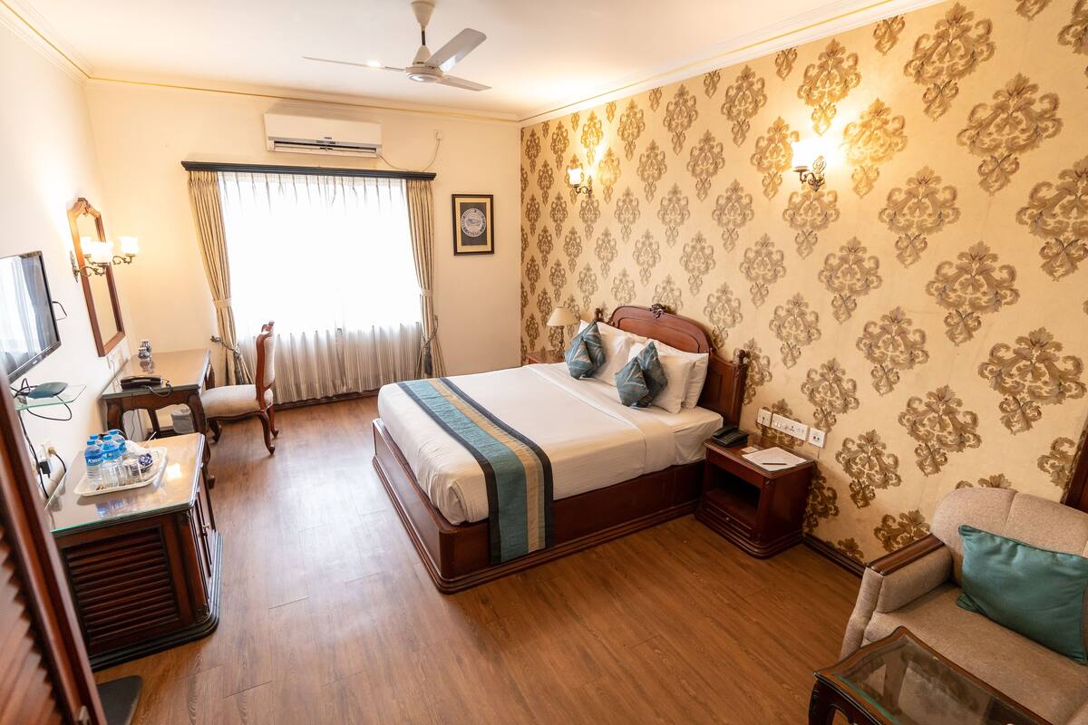 Ein Hotelzimmer mit Bett, Schreibtisch mit Computer, Stuhl, Sofa und Fernseher.