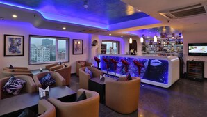 A modern bar area with seating, a bar counter, and a city view. - The Lindsay (Kolkata)