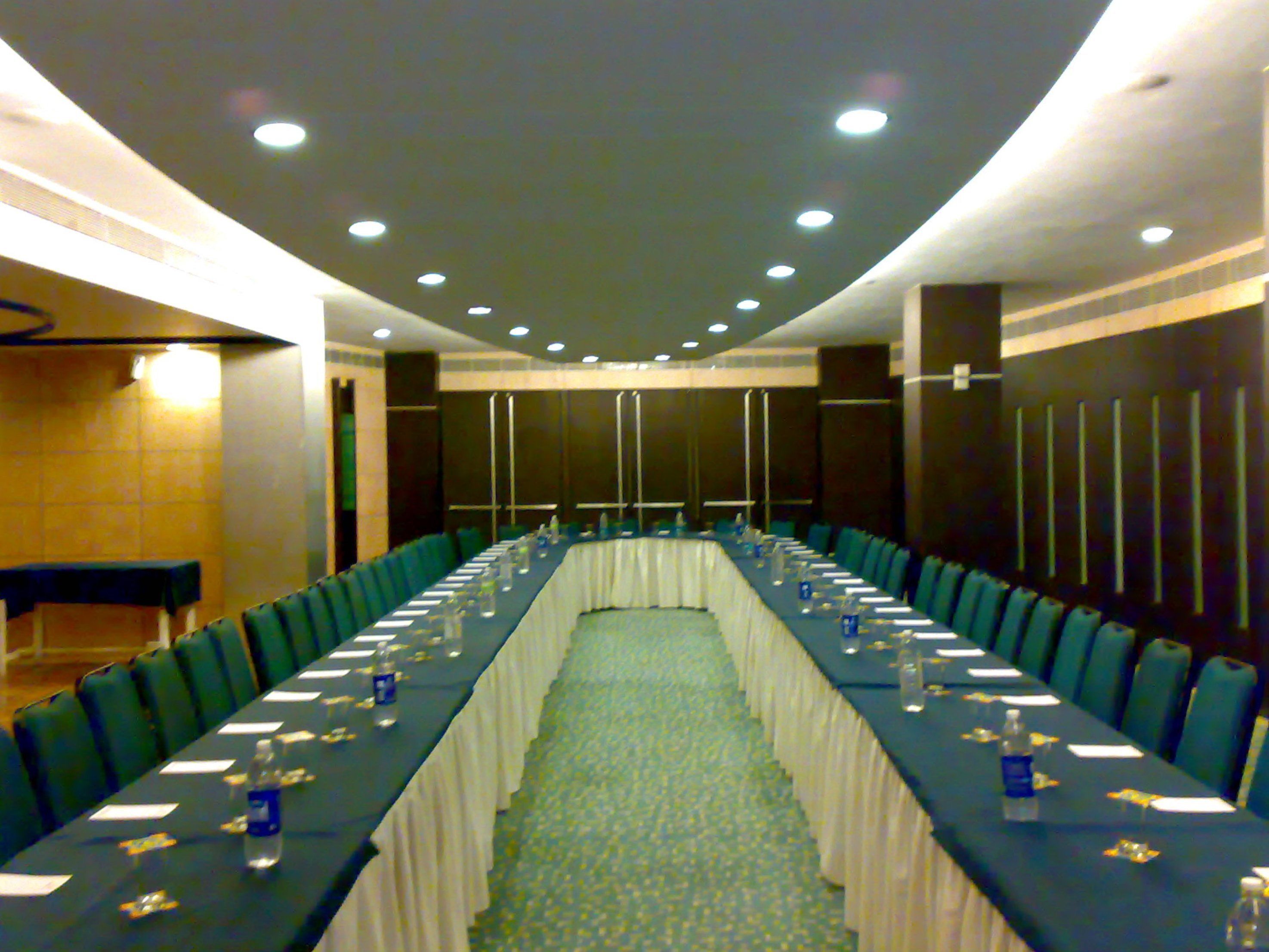A conference room with a long table, chairs, and a carpeted floor.