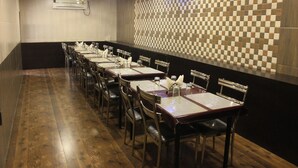 A long dining area with multiple tables and chairs, air conditioning, and a patterned wall. - Hotel Fortune (Mumbai)