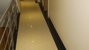 A long, narrow hallway with a tiled floor and a metal railing on one side. - Hotel Fortune (Mumbai)