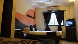 A hotel room with a bed, a desk, a television, and an air conditioning unit. - Hotel Fortune (Mumbai)