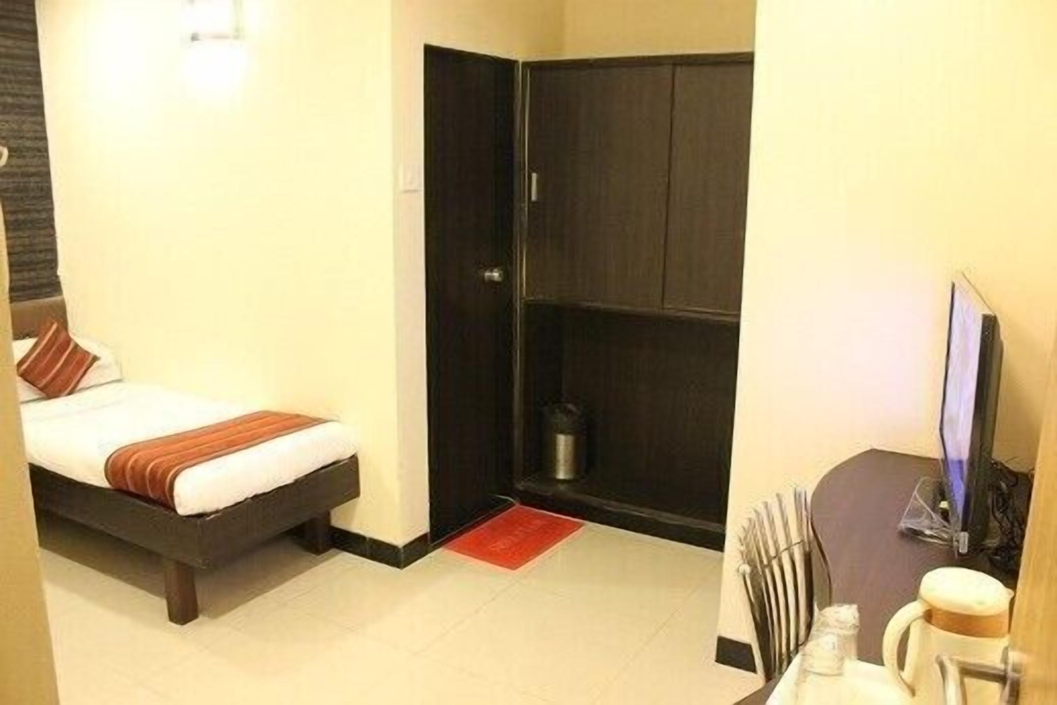 A hotel room with a bed, a desk with a computer, and a cabinet.