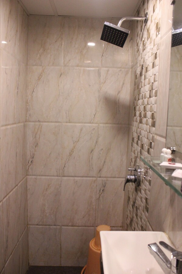 Un baño moderno con cabina de ducha de vidrio, lavamanos blanco y pared de azulejos con diseño de mosaico.