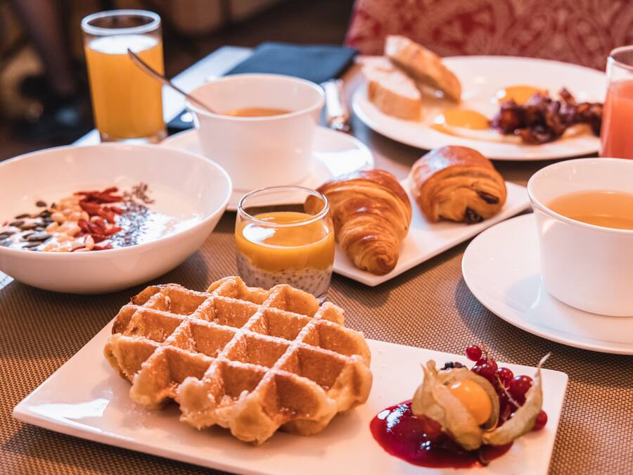 A breakfast setting with waffles, croissants, and various beverages on a table.