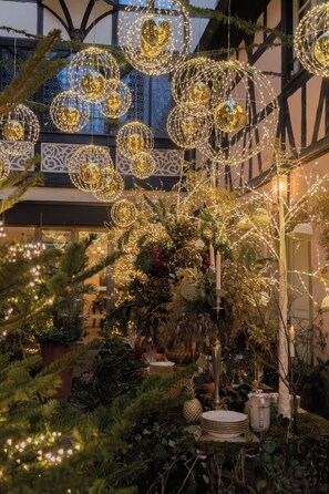 A courtyard with hanging spherical light fixtures and a variety of plants.
