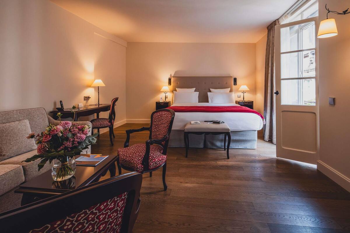 Una habitación de hotel con cama, escritorio, silla, sofá y ventana.
