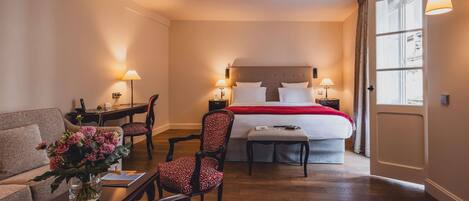 A hotel room with a bed, a desk, a chair, a sofa, and a window.