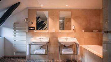 Une salle de bain moderne avec deux lavabos, un grand miroir et un sol carrelé en pierre.