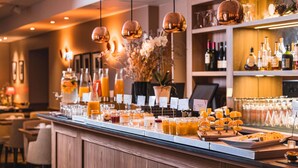 A bar area with a variety of drinks, a selection of bottles, and a wooden counter.