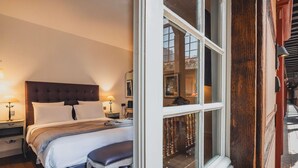 A bedroom with a large bed, bedside tables, a bench, and a window with a view of the outside.