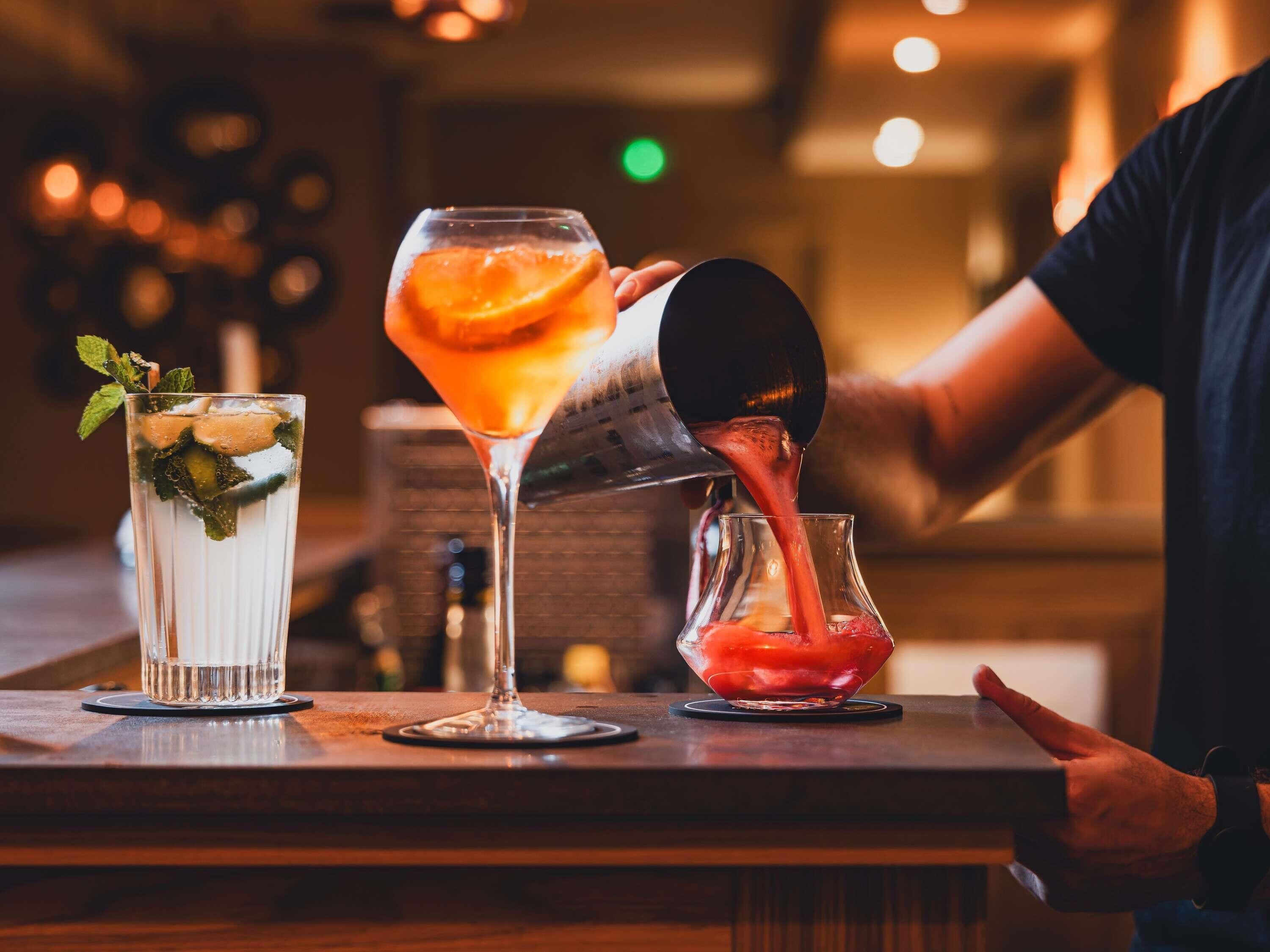 A bartender pouring a drink into a martini glass.