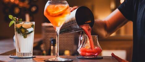 A bartender pouring a drink into a martini glass.