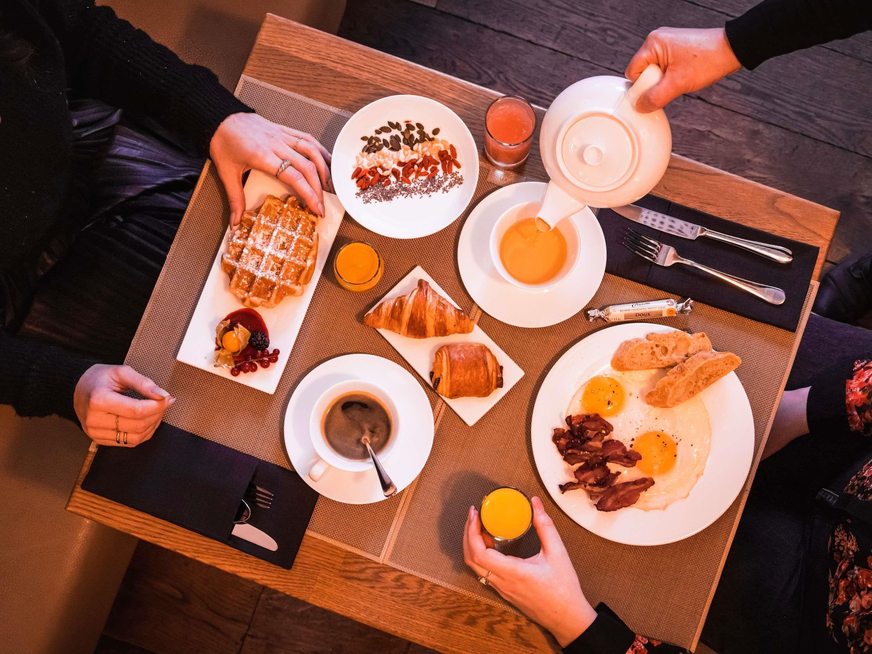 Ein Frühstückstisch mit Waffeln, Croissants, Eiern und Kaffee.
