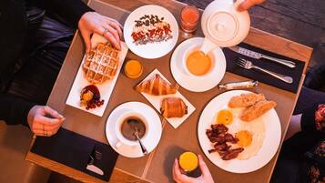 Ein Frühstückstisch mit Waffeln, Croissants, Eiern und Kaffee.