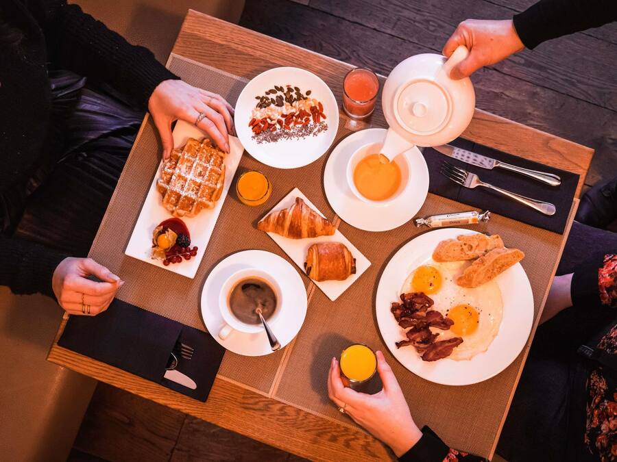 Ein Frühstückstisch mit Waffeln, Croissants, Eiern und Kaffee.