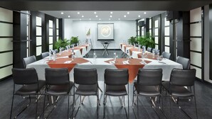 A conference room with a long table, black chairs, and water bottles. - Regale Inn (New Delhi)