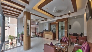 A spacious lobby with a reception desk, seating area, and a staircase leading to an upper level. - Regale Inn (New Delhi)