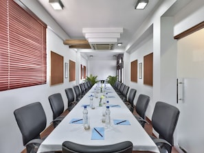 Ein Konferenzraum mit einem langen Tisch, schwarzen Stühlen und einer weißen Tischdecke.