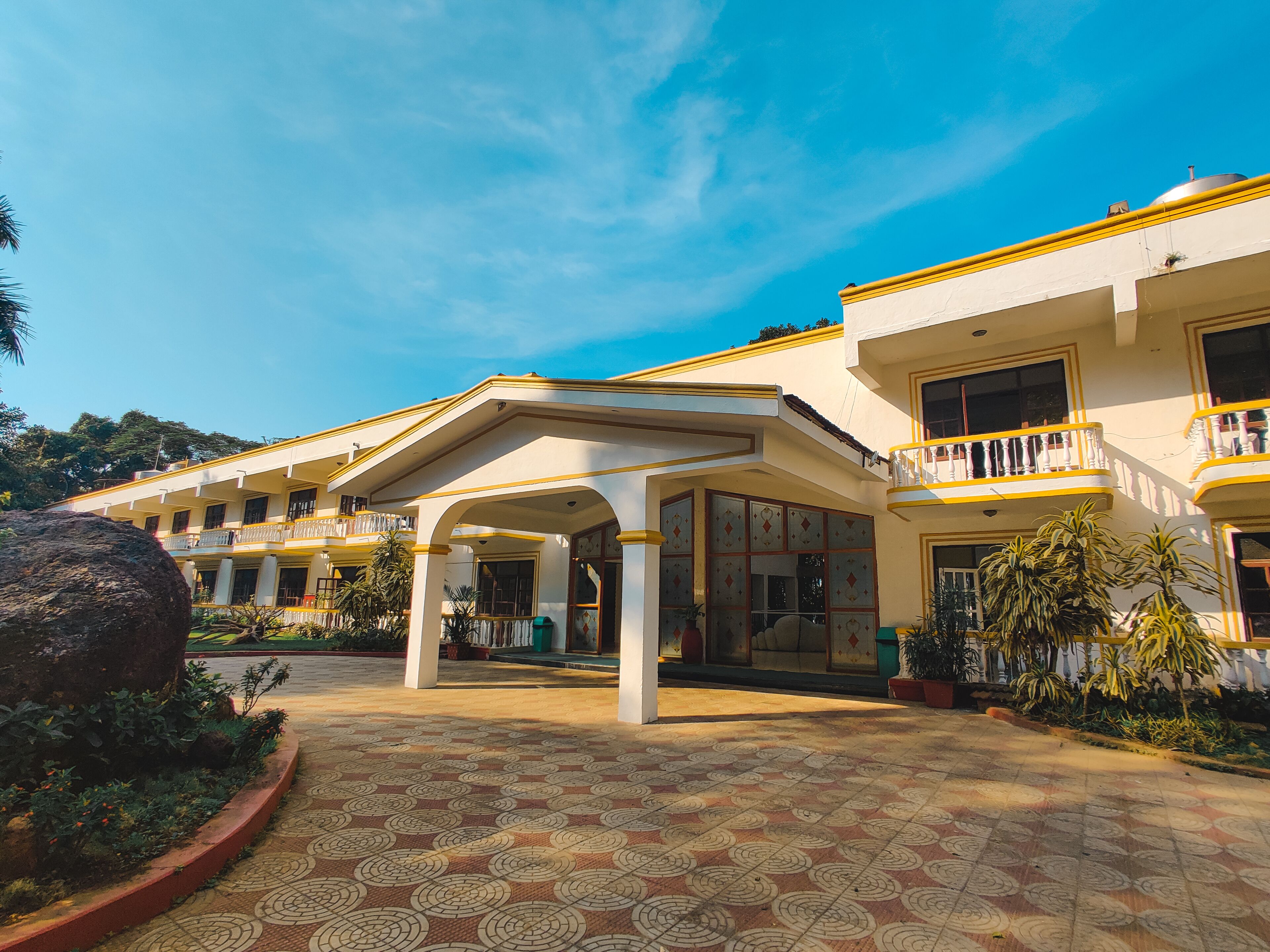 A hotel with a covered entrance, multiple balconies, and a patterned tiled courtyard.