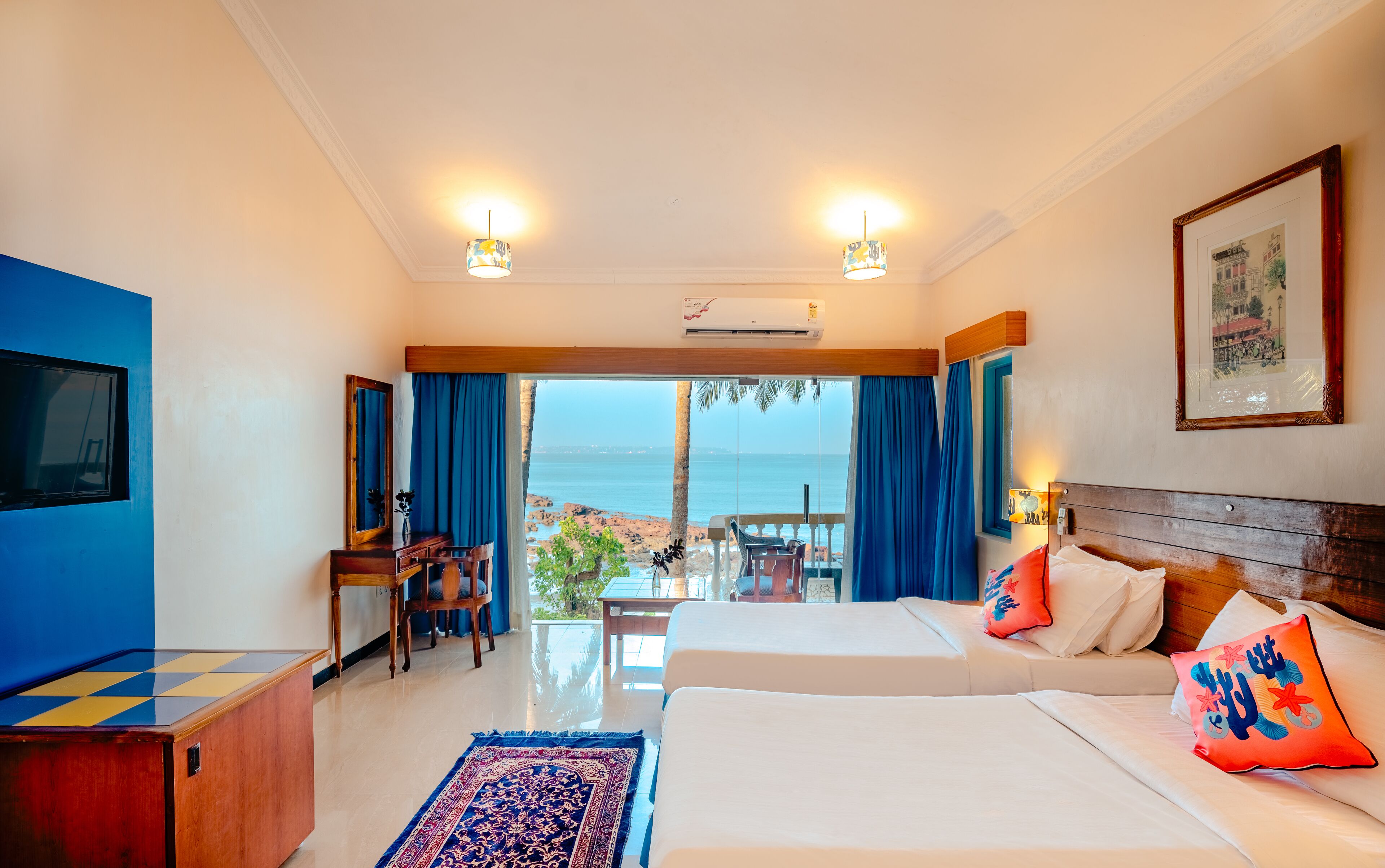 A hotel room with a large bed, a desk, and a view of the sea.