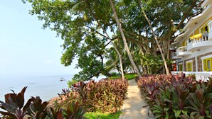 Un sendero bordeado de plantas tropicales que lleva a un edificio con balcones con vistas al mar.