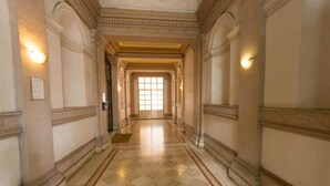 A corridor with marble flooring, classical columns, and wall sconces. - Fitzroy Allegria Suites (Rome)