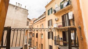 A narrow alleyway between buildings with balconies, a wrought iron gate, and a concrete wall. - Fitzroy Allegria Suites (Rome)