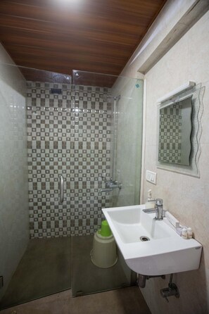 A bathroom with a shower, a sink, and a mirror. - Ontime Hotel (Mumbai)