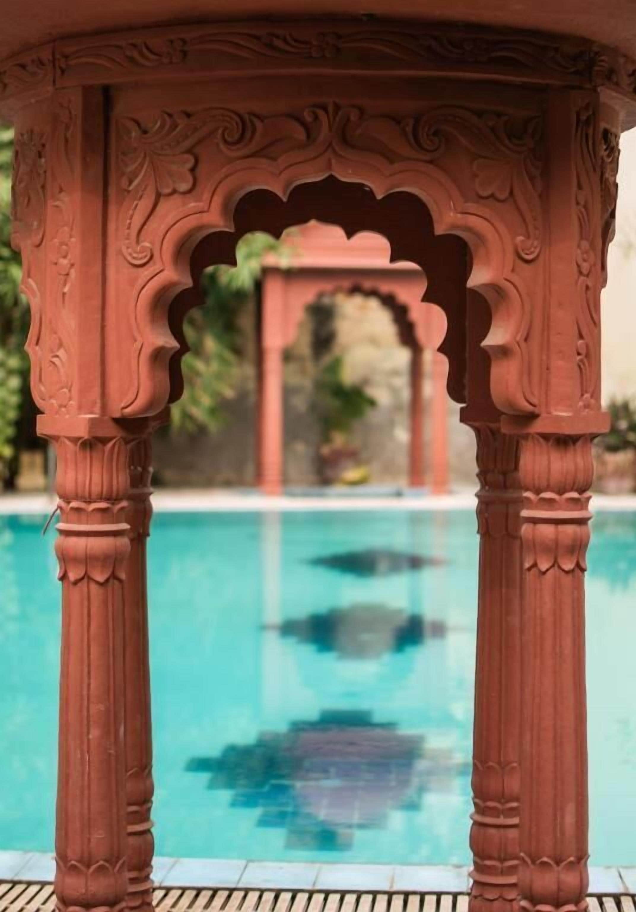Un espace piscine agrémenté de colonnes décoratives et offrant une vue dégagée sur l’eau.