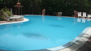 A swimming pool with lounge chairs and a gazebo. - Bissau Palace (Jaipur)