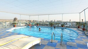 Una piscina interior con suelo a cuadros, sillones de descanso y plantas en macetas.