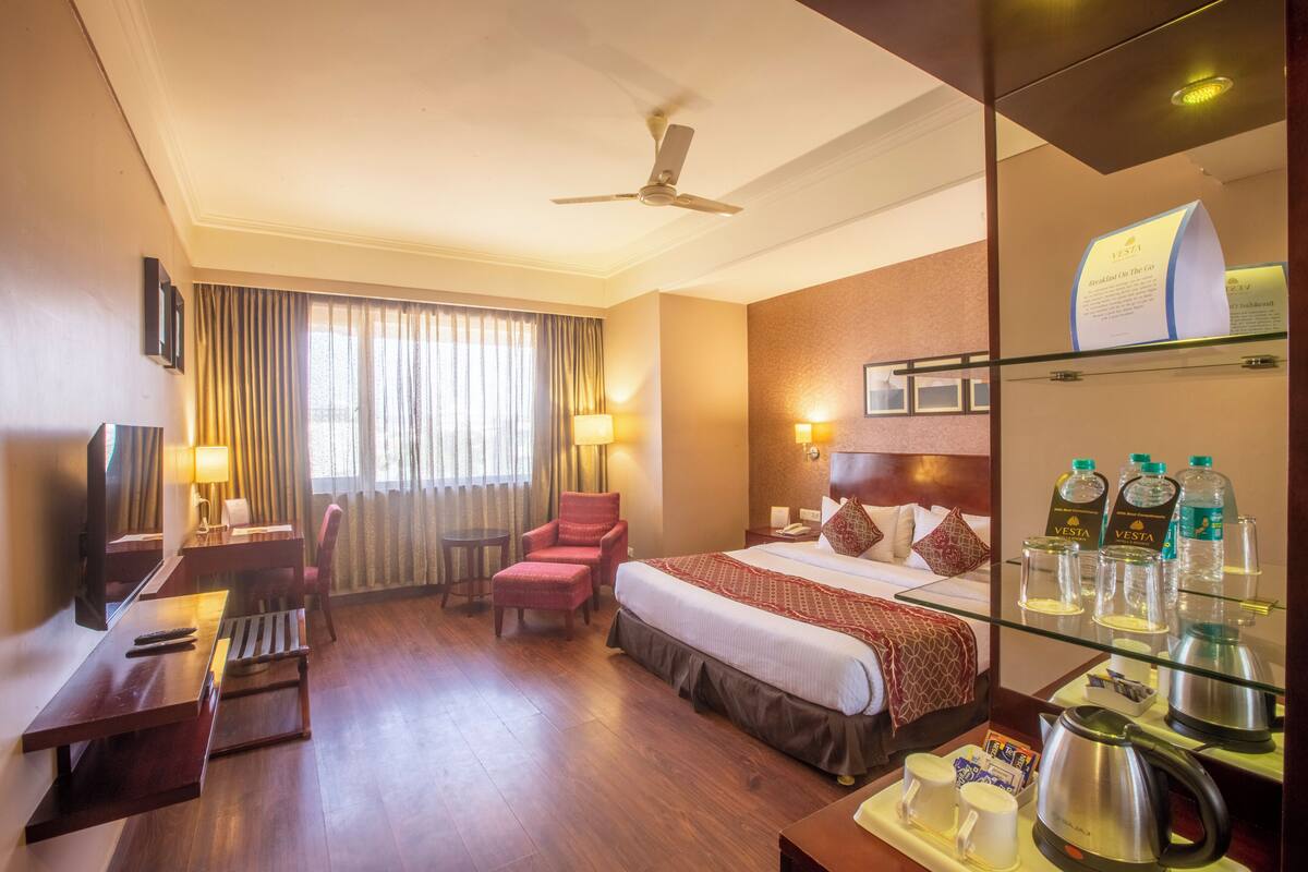 Une chambre d’hôtel équipée d’un lit, d’un bureau, d’une chaise, d’une télévision et d’un mini-bar.