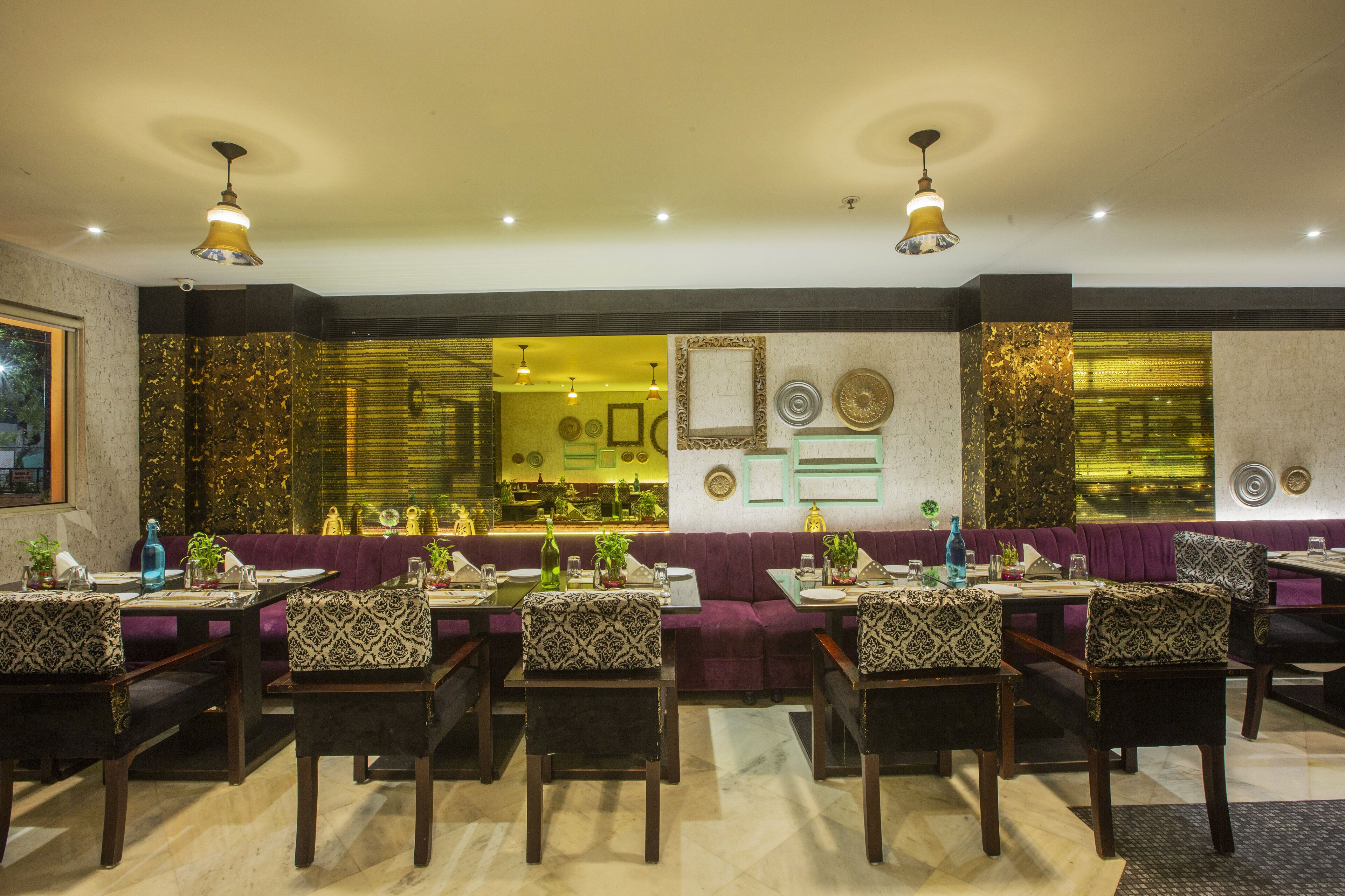 Un restaurant avec des banquettes violettes et des tables en bois, doté d’un sol en marbre et d’éléments décoratifs sur les murs.