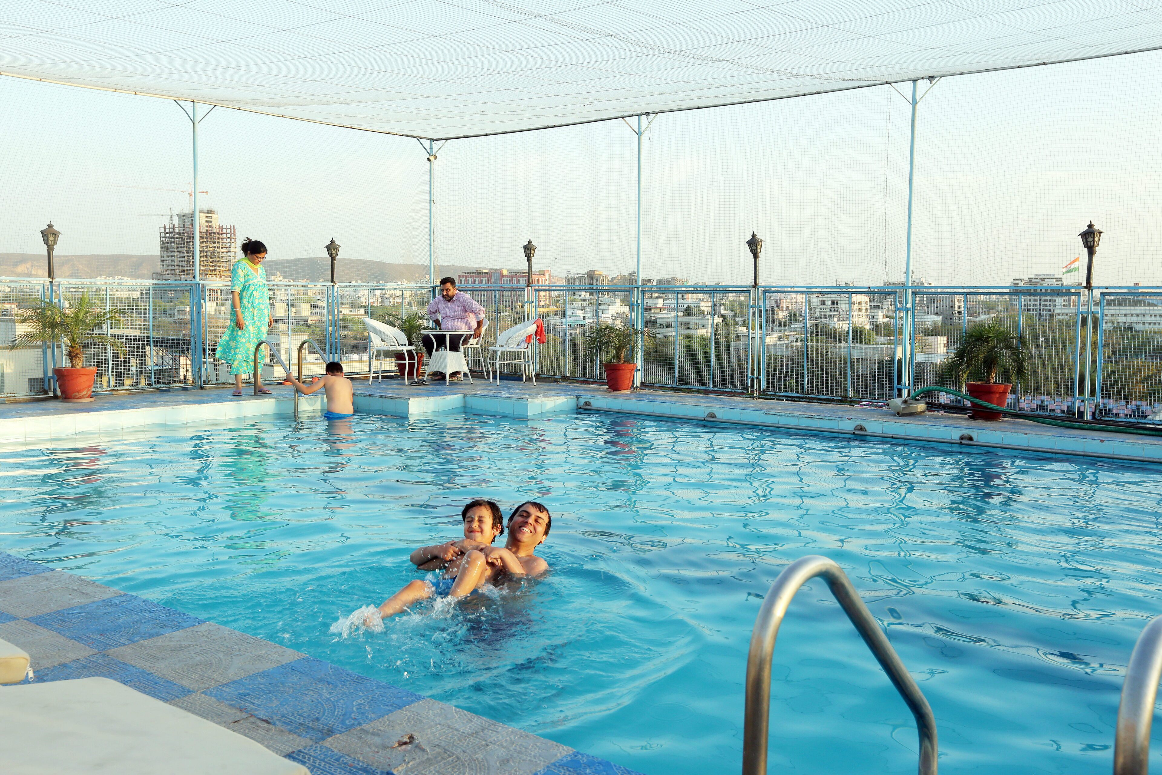 Una piscina techada, una piscina al aire libre, sombrillas