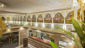 Un vestíbulo de hotel con techo decorativo, una recepción y vistas al estacionamiento.