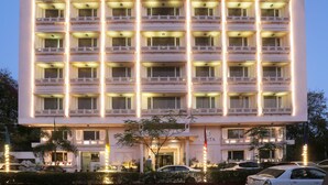 Un hotel de varios pisos con fachada simétrica, balcones en cada planta y una entrada bien iluminada.