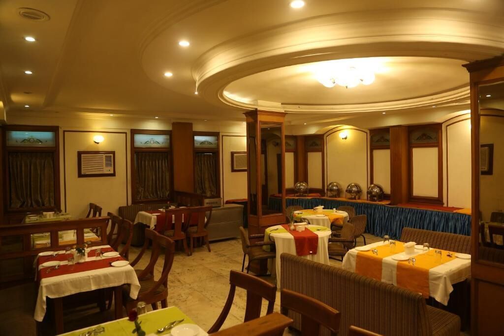 A restaurant with round tables, wooden chairs, and a blue tablecloth.