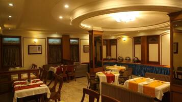 A restaurant with round tables, wooden chairs, and a blue tablecloth.