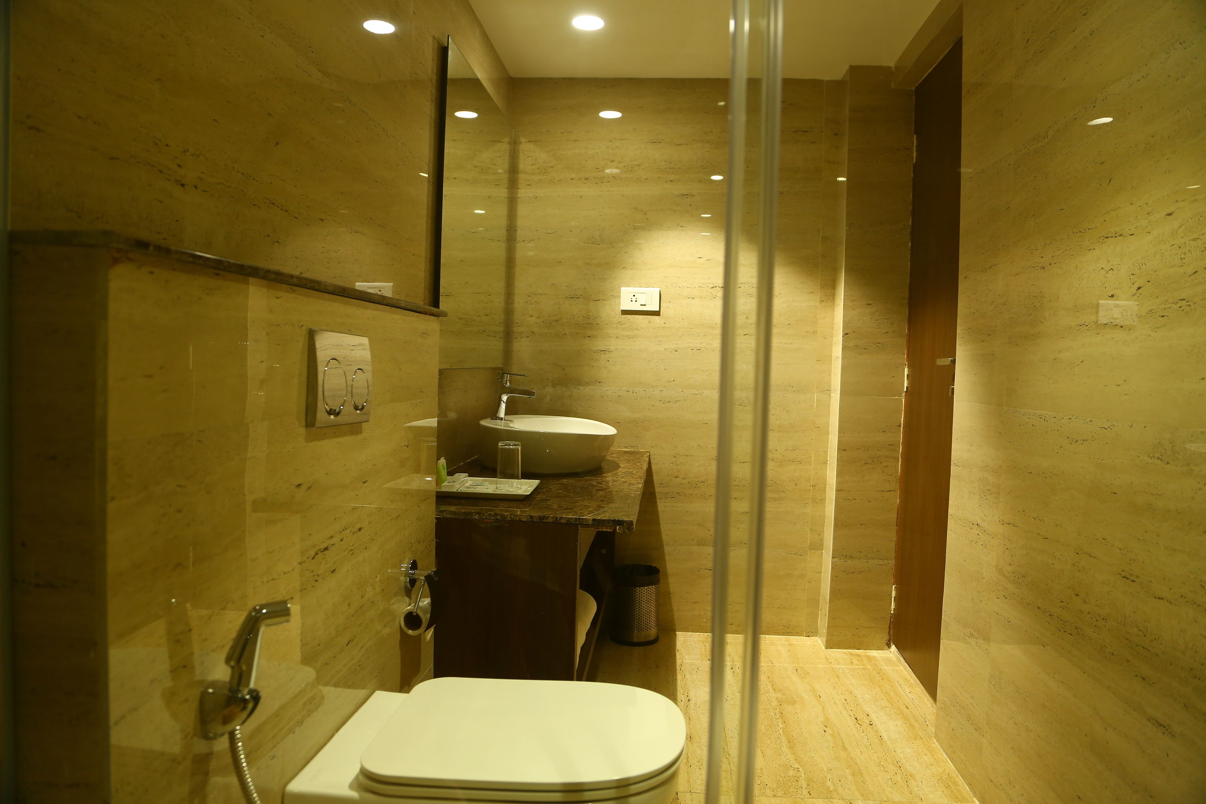 A modern bathroom with a glass-enclosed shower, a white sink, and a toilet.