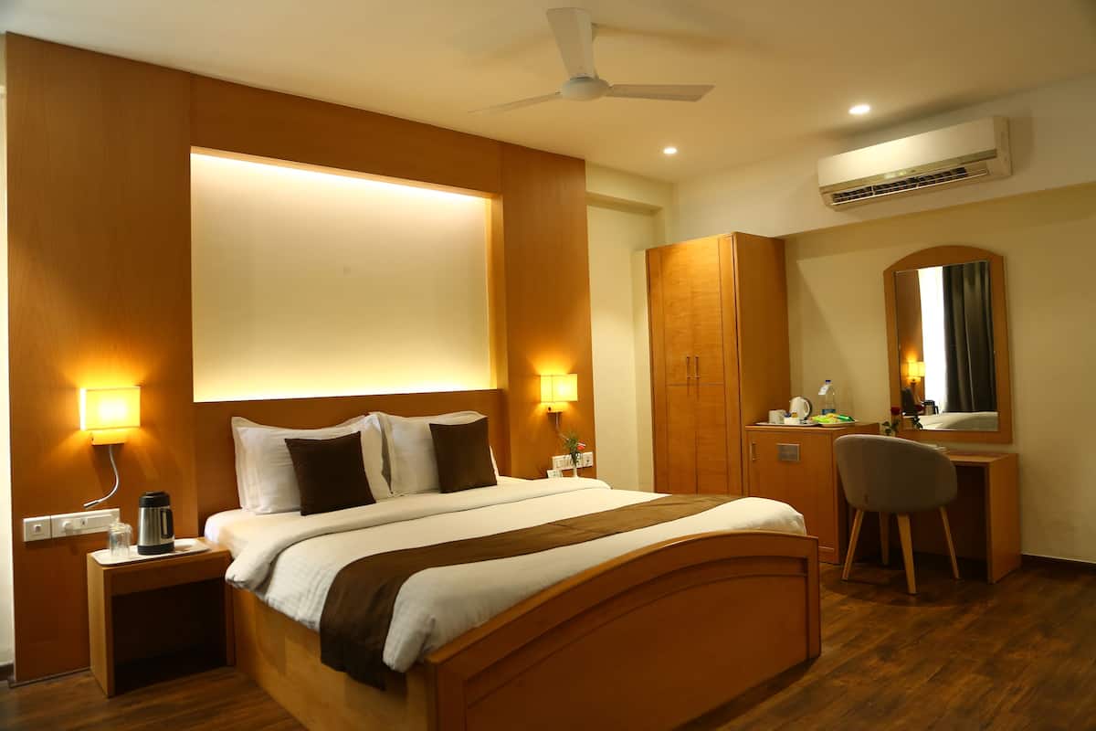 Habitación de hotel con cama, mesitas de noche, escritorio, silla, ventilador de techo y aire acondicionado.