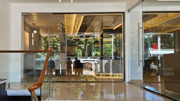 A modern lobby with a glass entrance, a marble staircase, and a contemporary chandelier. - Hotel Mount Manor (Chennai)