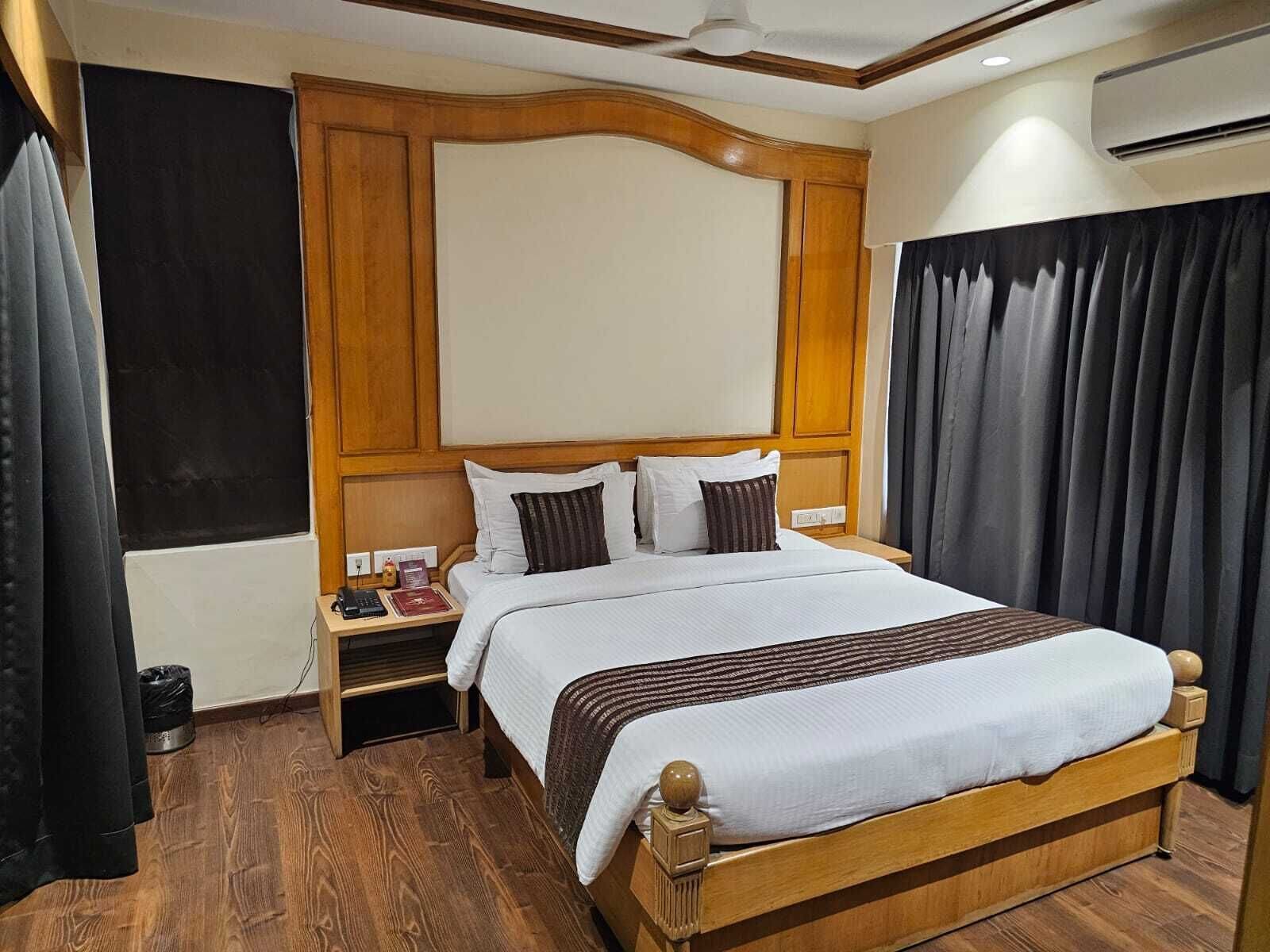 A hotel room with a large bed, wooden headboard, bedside tables, and a ceiling fan.