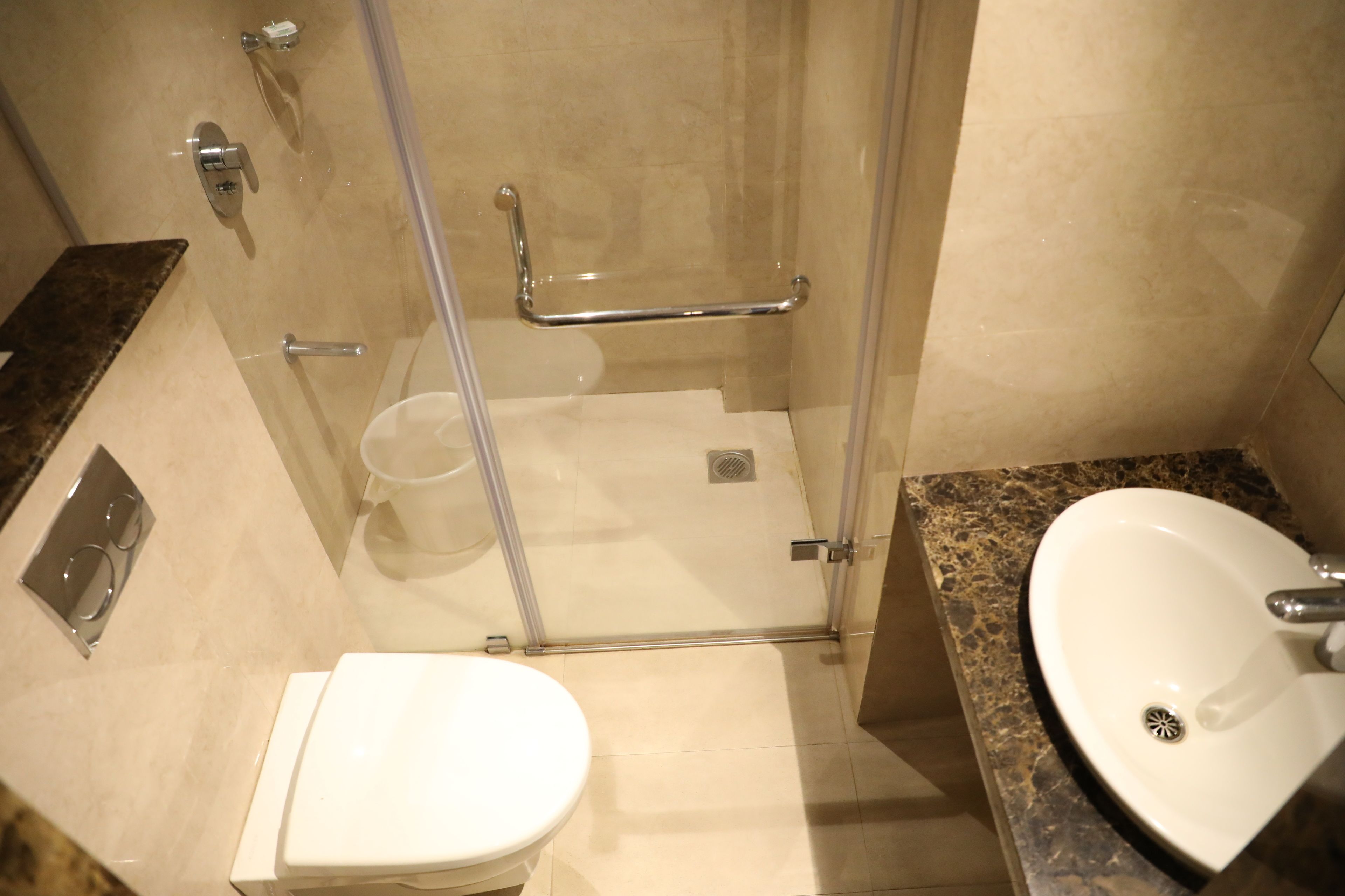 A bathroom with a toilet, a sink, a shower with a glass door, and a marble countertop.