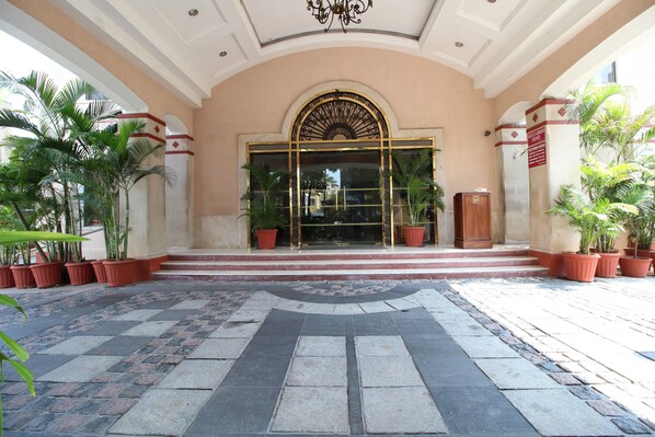 A hotel entrance with a grand archway, potted plants, and a stone-paved walkway. - Beverly Hotel (Chennai)